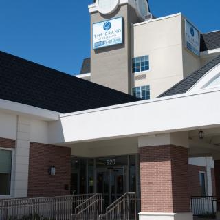 Entrance of a modern hospital building under a clear blue sky.