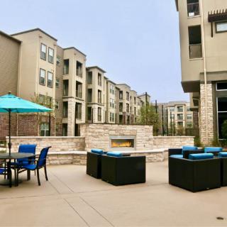Modern apartment complex with outdoor seating and a fireplace on the patio.
