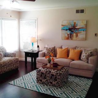 A cozy living room featuring a comfortable sofa with colorful pillows, an armchair, and a coffee table on a patterned rug.