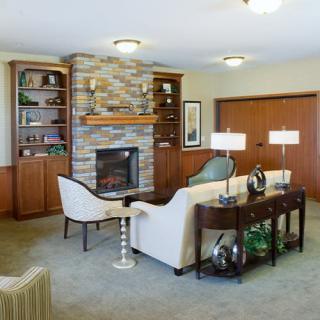 A cozy living room with a stone fireplace, comfortable seating, and elegant wooden shelving.