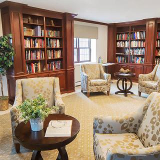 A cozy library space with bookshelves, armchairs, and a small table.