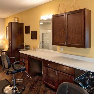 A modern hair salon interior featuring stylish chairs, wooden cabinets, and large mirrors.