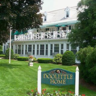 A charming home with a lush garden and a sign reading 'Doolittle Home'.