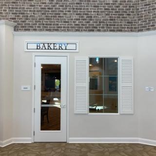 A small bakery storefront with a brick wall above and a door flanked by a window.
