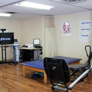 A well-equipped physical therapy clinic with treatment tables and exercise machinery.