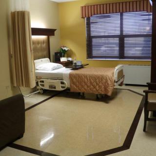A hospital room featuring a single bed, curtain, and window with blinds.