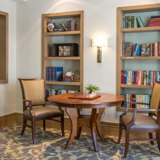 A cozy reading area featuring two bookshelves, a small wooden table, and chairs.