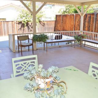 A cozy outdoor patio with seating and plants under a gazebo.