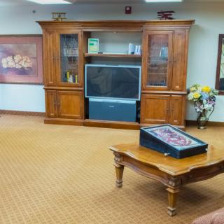 A cozy living room with a large wooden cabinet housing a television, and a coffee table in the center.