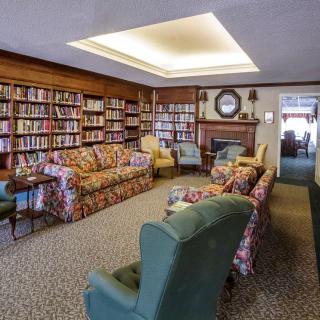 A cozy library with bookshelves, comfortable armchairs, and a fireplace.