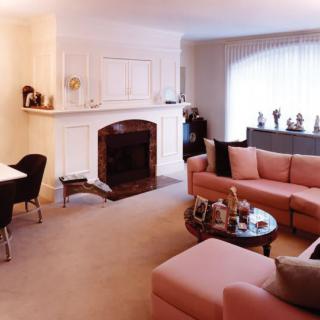 A cozy living room featuring a fireplace, a pink sectional sofa, and a stylish coffee table.
