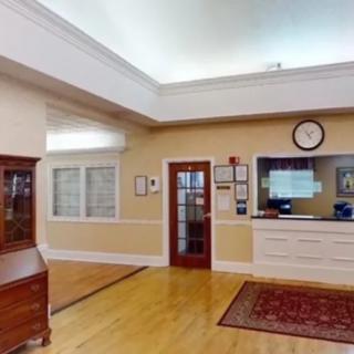 A well-lit reception area with a desk, clock, and wooden furniture.