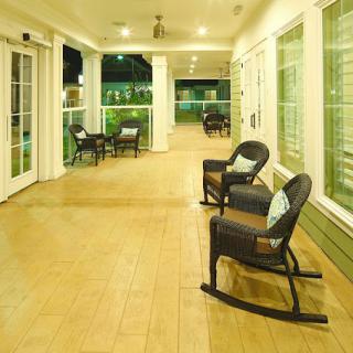 A well-lit porch with rocking chairs, providing a cozy and inviting outdoor seating area at night.
