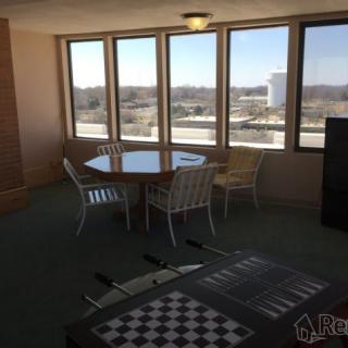 A bright room featuring a dining table with chairs, large windows, and a foosball table.