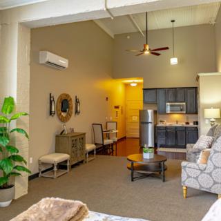 A modern open-plan apartment interior featuring a cozy living area and kitchen with contemporary furnishings and decor.