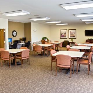 A well-lit meeting room with multiple tables and chairs arranged for gatherings.