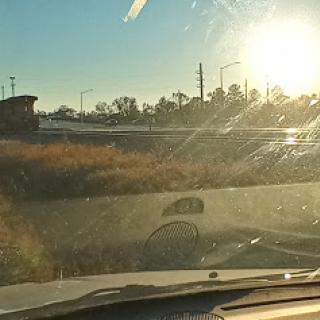 A scenic view from inside a car, capturing the warm glow of the sunset over a grassy road.