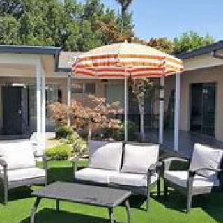 A relaxing patio area with comfortable seating and a striped umbrella.