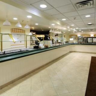 An empty buffet restaurant interior with tiled flooring and a well-lit serving counter.