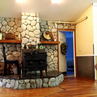 A cozy living room with a stone fireplace and a wood stove, complemented by hardwood flooring.