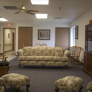 A cozy waiting room with a patterned sofa and wooden chairs.