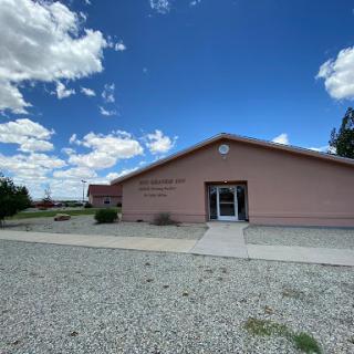 A pink building under a blue sky with fluffy white clouds.