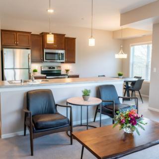 A modern open-concept kitchen and living room with stylish furniture and stainless steel appliances.