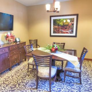 A cozy dining room setup with a table, chairs, wall art, and a television.