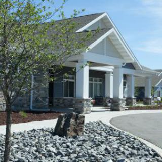 A modern building with a landscaped entrance and stone accents.