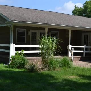 A ranch-style house with a front porch and surrounding greenery.