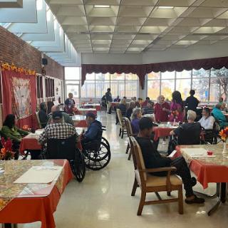 A lively community dining area filled with elderly individuals enjoying their time together.