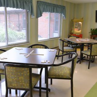 A bright and inviting dining area with tables and chairs, featuring large windows and decorative curtains.