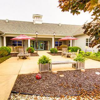 A well-maintained outdoor patio with seating and umbrellas, surrounded by landscaping.