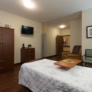 A modern hotel room featuring a neatly made bed, a television on the wall, and comfortable furniture.