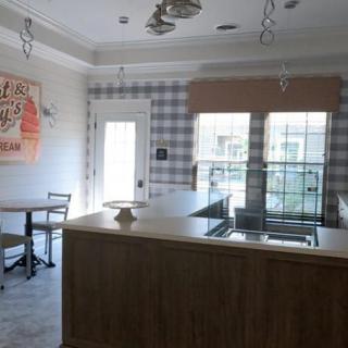 A modern kitchen with a central counter, plaid wallpaper, and natural lighting from large windows.