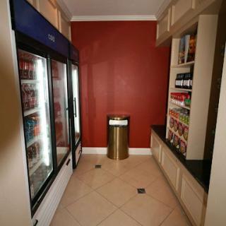 A modern pantry area featuring beverage coolers and snack shelves against a vibrant red wall.