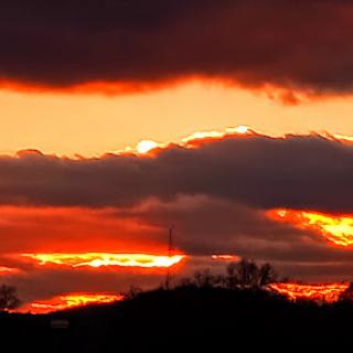 A breathtaking sunset paints the sky with vibrant hues of orange and red, framed by dark clouds.