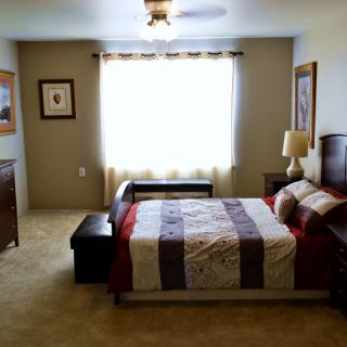 A cozy and well-lit bedroom with a neatly made bed, side tables, and decorative artwork.