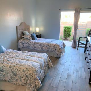 A cozy bedroom with twin beds and natural light streaming in through the curtains.