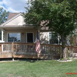 A residential house with a wooden deck and an American flag displayed at the front.