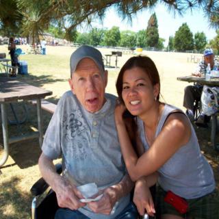 A man and a woman sitting together outdoors in a park.