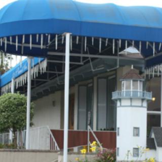 A building with a blue awning and a small lighthouse replica outside.