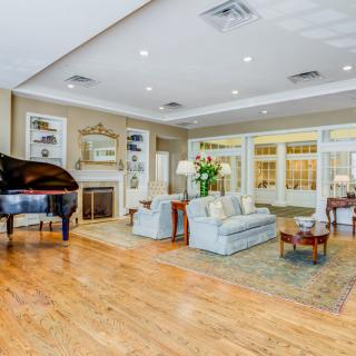 A spacious and elegantly decorated living room featuring a grand piano, comfortable seating, and a cozy fireplace.