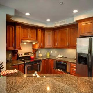 A modern kitchen featuring wooden cabinets, a granite countertop, and stainless steel appliances.
