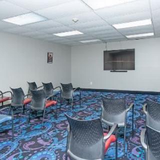 An empty meeting room with chairs arranged and a television mounted on the wall.