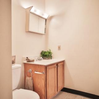 A small, neatly arranged bathroom with a wooden cabinet and mirror above the sink.