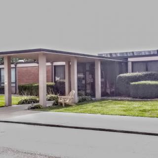 A contemporary building with a well-maintained lawn and a covered entrance.