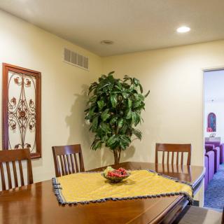 A cozy dining room with a wooden table and chairs, decorated with a centerpiece and surrounded by wall art and an indoor plant.