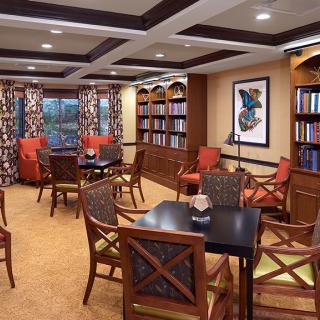 A cozy library reading room with bookshelves, tables, and comfortable chairs.