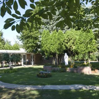 A serene garden with a statue surrounded by trees and well-maintained lawns.